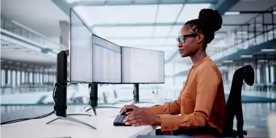 Gebotsabgabe Frau arbeitet am Laptop in einem modernen Büro.