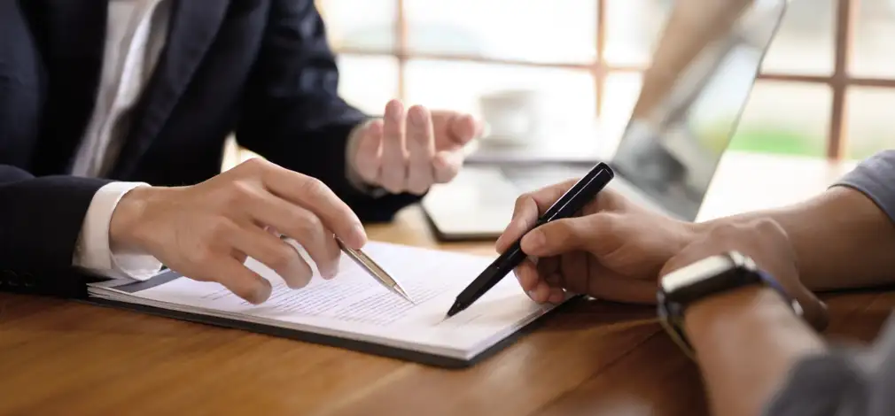 Zwei Personen sitzen am Tisch und besprechen einen Vertrag, um einen Acker für Windrad zu verpachten. Zwei Personen sitzen am Tisch und besprechen einen Vertrag, um einen Acker für Windrad zu verpachten.