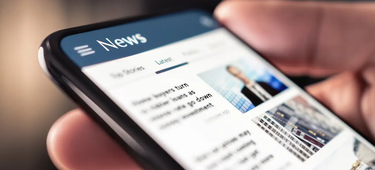 Presse und Medien – Aktuelle Informationen von Caeli Wind Hand hält Smartphone mit geöffneter News-App.