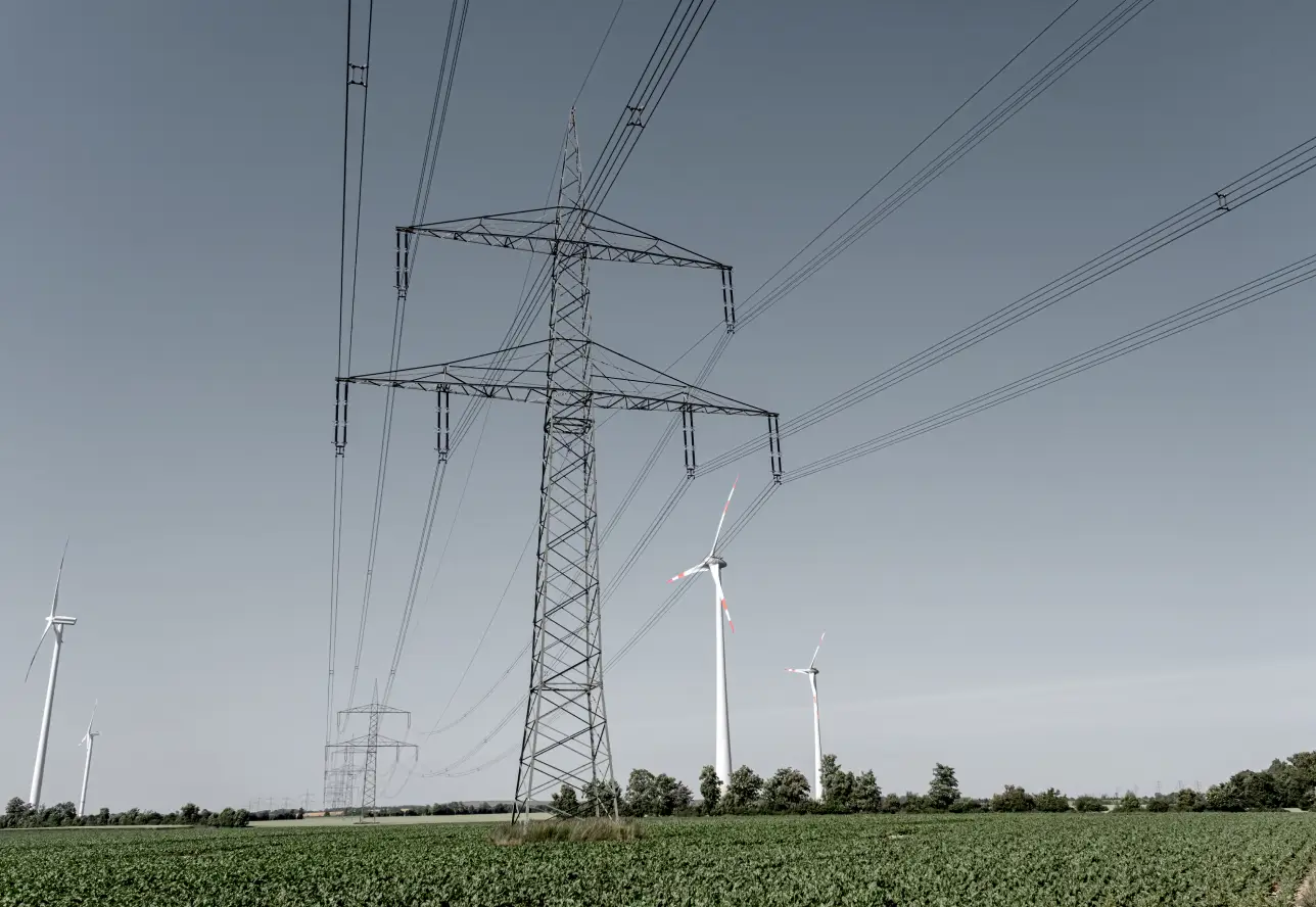 Windkraftanlagen und Hochspannungsleitung auf einem Feld.