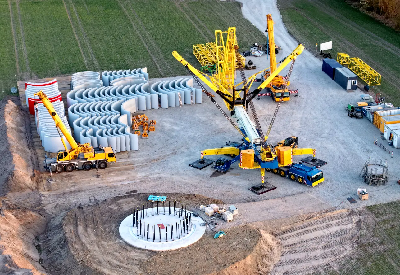 Montageplatz einer Windkraftanlage mit Kran und Bauteilen.