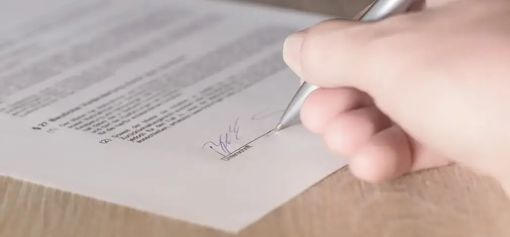 Hand hält einen Stift und unterschreibt einen Vertrag zum Flächenpooling.
