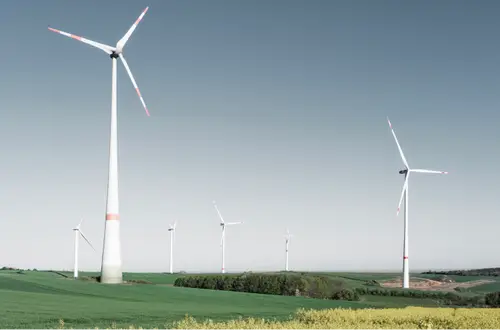 Windräder auf einem Hügel im Saarland, umgeben von Feldern.