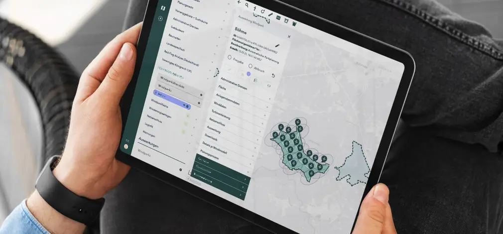 Hände halten ein Tablet mit digitaler Softwarelösung von Caeli Wind, Anzeige einer Karte und Menüoptionen.