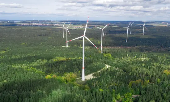Argumente gegen Windkraftanlagen im Wald – zwischen Mythen und Fakten Windpark in einer bewaldeten Landschaft, Windräder ragen über die Baumwipfel.