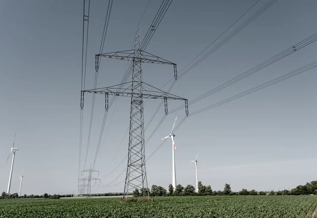Windkraftanlagen und Hochspannungsleitung auf einem Feld.