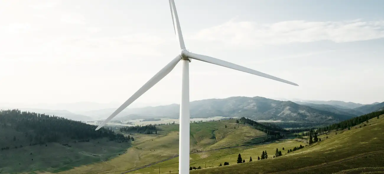 Windrad ragt aus nebliger, hügeliger Landschaft hervor. Windrad ragt aus nebliger, hügeliger Landschaft hervor.