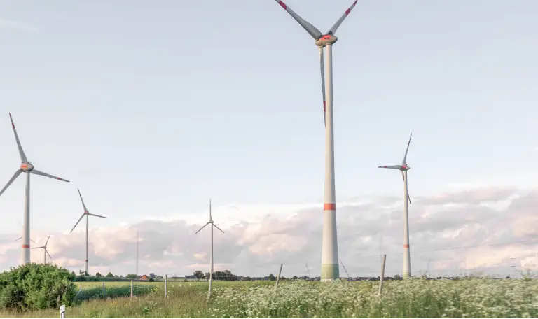 Windräder stehen in der Abenddämmerung in der hessischen Landschaft mit Feldern.