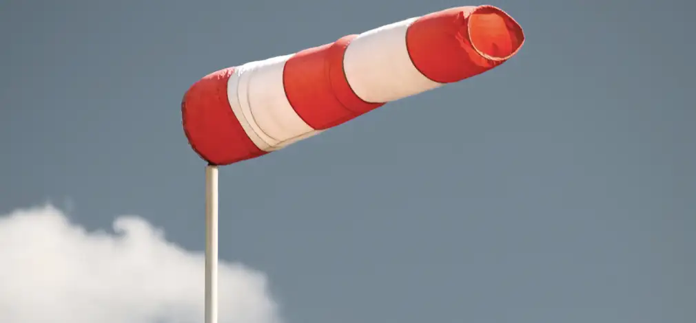 Windsack weht vor hellblauem Himmel und steht für Windmessung. Windsack weht vor hellblauem Himmel und steht für Windmessung.